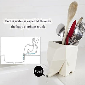 A whimsical cutlery holder shaped like a white elephant, featuring spoons, forks, and a wooden spoon inside. Its trunk cleverly extends over the sink edge for water drainage. An inset diagram shows water flowing from the trunk marked Point, making it the perfect kitchen utensil storage solution.