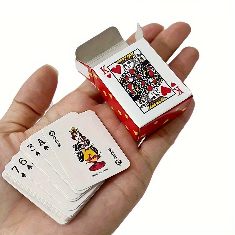 A small, unopened deck of playing cards rests in the palm of a hand. The top card visible on the deck is the King of Hearts. Mini playing cards, deck of cards, pocket-sized cards, travel game.