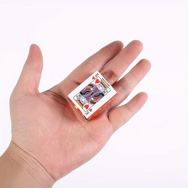 A small, unopened deck of playing cards rests in the palm of a hand. The top card visible on the deck is the King of Hearts. Mini playing cards, deck of cards, pocket-sized cards, travel game.