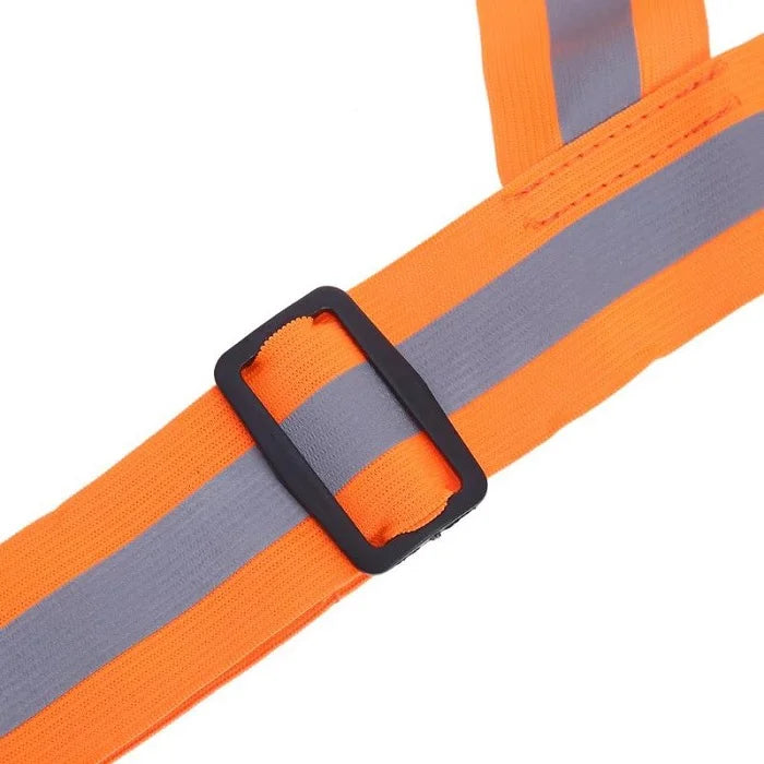 A close-up shows the adjustable black plastic buckle and reflective silver stripe on an orange high-visibility safety vest belt. The strap material is a durable woven fabric. High visibility vest, reflective belt, safety wear, workwear, adjustable strap, home improvement, tool store, home essential.