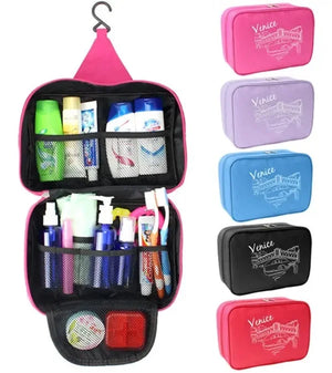 A pink Venice Travel Cosmetic Organizer Bag is shown fully opened and hanging, filled with various travel-sized toiletries such as shampoo, toothpaste, lotions, and toothbrushes. To the right are five closed versions of the same bag in different colors: pink, light purple, light blue, black, and red, each featuring a white line drawing of Venetian architecture and the word "Venice." Venice Travel Cosmetic Organizer Bag, hanging toiletry bag, travel bag organizer, makeup organizer, travel essentials, bathro