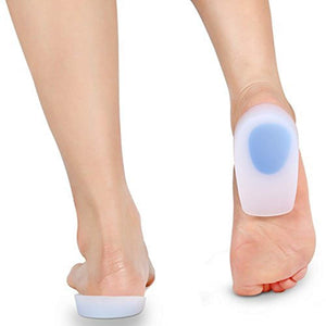 The image shows a close-up view of the back of two bare feet, each with a clear silicone heel cup featuring a blue gel insert placed underneath the heel.silicone heel cup, heel cushion, heel support, foot care, shoe inserts, orthopedic insoles, health and personal care.