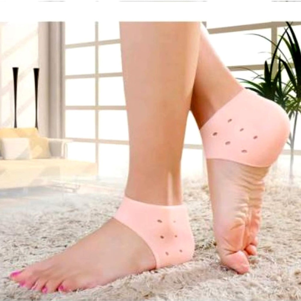 A close-up shows two bare feet, each wearing a beige silicone heel protector that covers the heel and has small ventilation holes.silicone heel protector, heel sleeve, heel cushion, foot protection, plantar fasciitis, heel pain, foot care, health and personal care.