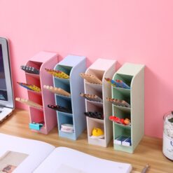 4 grid pen holder are placed on a desk, besides laptop. The first 4 grid pen holder is of pink color followed by blue, followed by cream, and lastly light green color. All the 4 grid pen holder are filled with pencils, pens, erasers, and other stationaries.