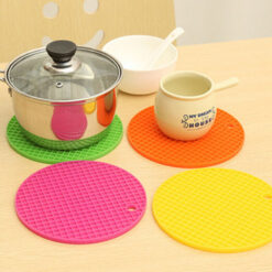 4 hot pot mats are shown in the picture. All the 4 hot pot mats are silicone trivet mat. The hot pot mats shown in the picture are of green, purple, yellow, and orange color. Hot vessel is placed on a green color heat resistant trivet mat and a cup is placed on an orange color heat resistant trivet mat.