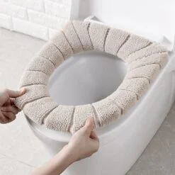 Lady is installing beige color soft toilet seat cushion on toilet seat.