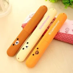 3 pieces cartoon toothbrush box of different colors is shown. All the three cartoon toothbursh box is placed on a small pillow for elegant presentation