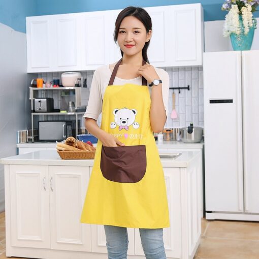 A girl is standing in kitchen wearing yellow color kitchen cooking apron.