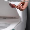 Lady is lifting toilet seat with the help of toilet seat cover lifter. A red color toilet seat lifter handle is used in the picture.