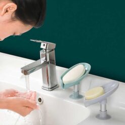 Woman is washing face using soap from a suction drain soap tray. Blue and grey color suction drain soap tray is shown.