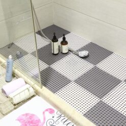 Rubber mats for shower is placed on a bathroom floor on which bottles of shampoo and conditioner is placed.
