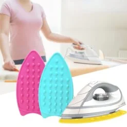 A woman is ironing her clothes. An iron is placed along with pink and blue color silicone hot iron mat.