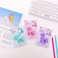 3 different colors beautiful unicorn eraser are placed on an office desk along with keyword, pencils, and A4 size book.