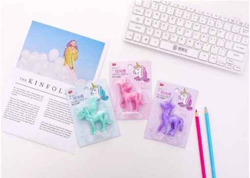 3 different colors beautiful unicorn eraser are placed on an office desk along with keyword, pencils, and A4 size book.