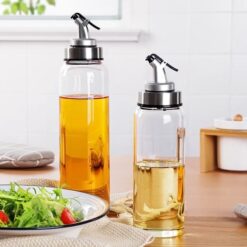 Plastic oil dispenser 1000ml is placed along with another oil dispenser and a plate of salad on a table.