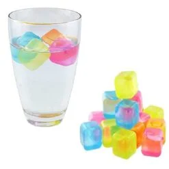 A glass filled with water and light up ice cubes. Few light up ice cubes are placed besides the glass.