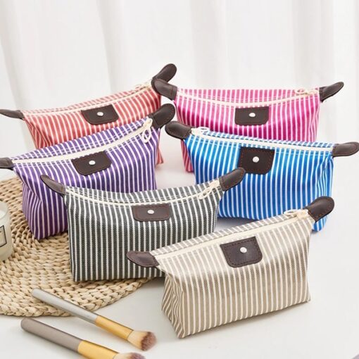 Travel cosmetic pouch presented in 6 different colors on a table besides makeup brush.