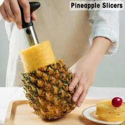 Pineapple corer and slicer tool is being used by a woman to draw pineapple slices from pineapple.