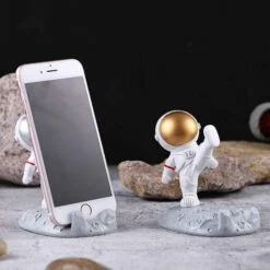 one astranaut cell phone holder is holding mobile phone and another astranaut cell phone holder is vacant.
