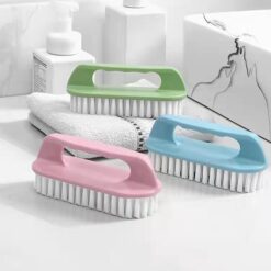 Soft bristle cleaning brush is presented in pink, blue, and green color on a table along with a napkin.