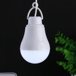 USB rechargeable led bulb is lighted in dark near plants.