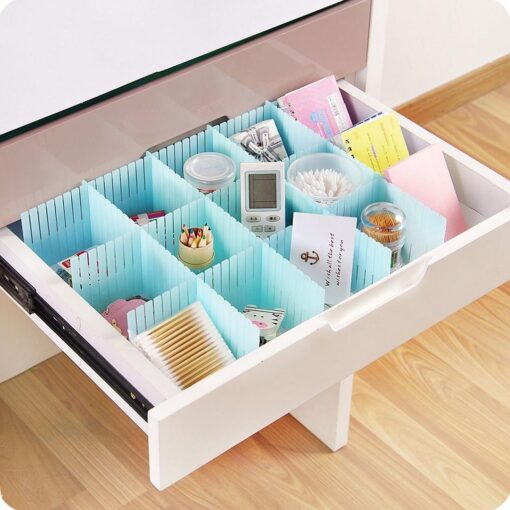 Blue color plastic drawer divider is being arranged in a drawer and things are placed in it.