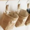 3 Jute wall mounted storage bag is hanged side by side on 3 different hooks.
