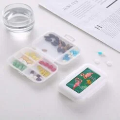 1 Travel pill case is open presenting all pills in an organized way. Another travel pill case is closed.