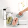 Grey color tile cleaning scrubber is used to clean washbasin. Green and Pink color tile cleaning scrubber is kept beside the washbasin