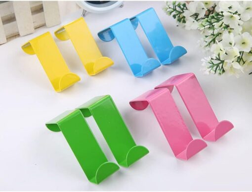 Yellow, blue, green, and pink color stainless steel over door hooks are placed on white color table besides flowers.