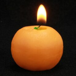 Orange shaped candle is lighted in a dark room.