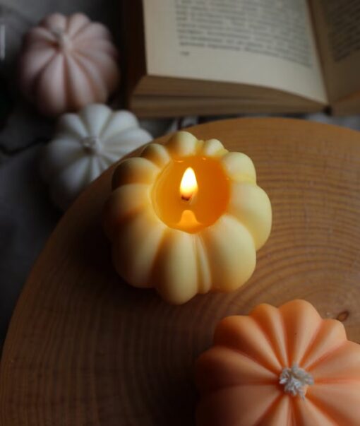 Two pumpkin shaped candles are kept on a table while other 2 pumpkin shaped candles are kept below the table.