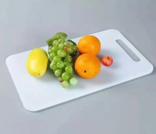 Mango, grapes, and oranges are kept on a white plastic chopping board.