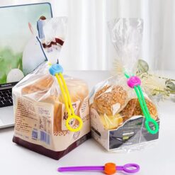 Blue and yellow combination sealing strap is used to seal a packet of bread. Purple and green color sealing strap is used to seal the packet of cookies