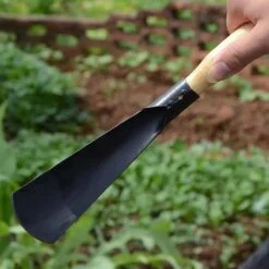 A guy is using flat gardening shovel while gardening.