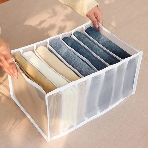 A man is using 7 compartment transparent clothes storage organiser to store his jeans and pants.