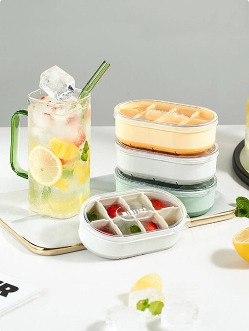 Ice cube tray with lid is shown in different colors besides a juice glass on the table.