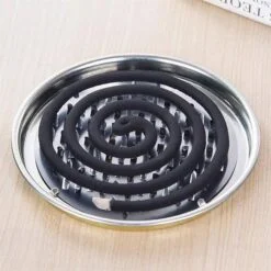 Black color coil is being placed in a stainless steel serrated mosquito coil holder
