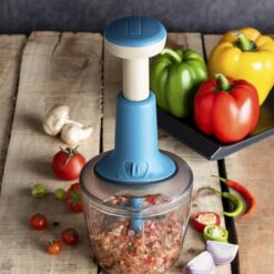 Blue and grey color fast vegetable chopper is being used to chop vegetables. Fast vegetable chopper is kept besides a tray filled with green, yellow, and red bell pepper.
