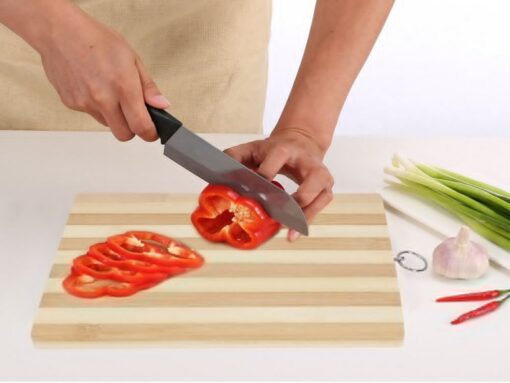 A man is cutting tomatoes on kitchen wood chopping board.