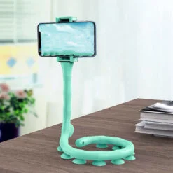 Snake mobile holder is holding a mobile in a horizontal way on an office desk besides books.