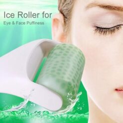 Green color ice roller face massager with white color handle is placed near woman's face.