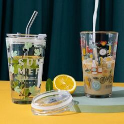 Glass tumbler with lid and straw is shown in 2 different prints on a yellow color table besides half lemon.