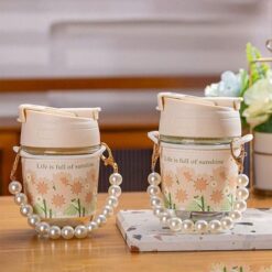 Cute Bracelet attached glass mug with lid and straw placed on a wooden table.