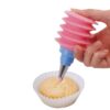 Squeeze bottle with nozzle is being used to decorate muffins.