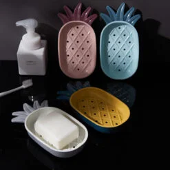Pineapple shaped plastic soap dish is displayed in pink, blue, yellow, and white color.