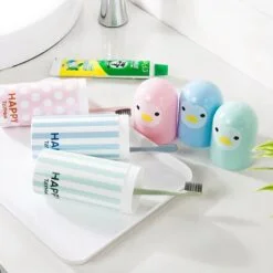 Toothbrush and toothpaste travel case in different colors are placed near wash basin.