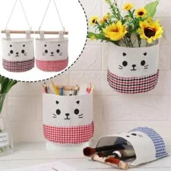 One wall mounted storage bag is filled with stationaries and another wall mounted storage bag is filled with flowers. Wall mounted storage bag which is fallen consists of makeup brushes