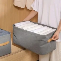 Woman is arranging clothes in a foldable clothes storage bag.