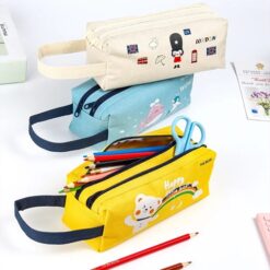Double zipper pencil case shown in 3 different colors and prints on a table along with pencils